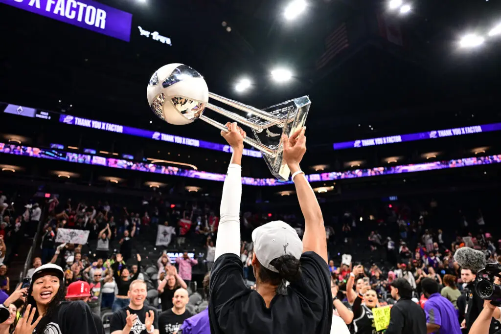 Las Vegas Aces star A'ja Wilson lifts the 2025 WNBA Championship trophy high over the crowd after the title game.