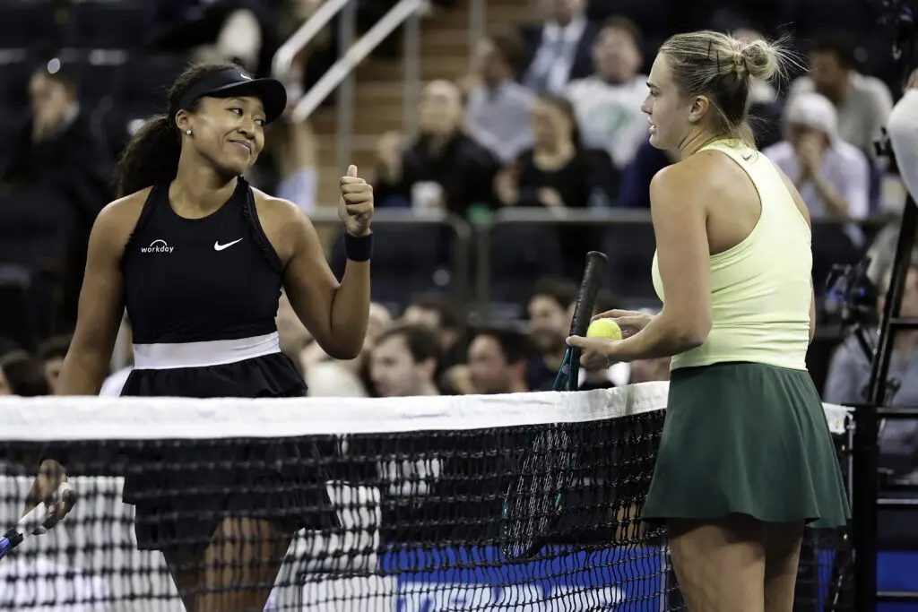 Naomi Osaka gives Aryna Sabalenka a thumbs up at the net during a 2025 tennis exhibition.