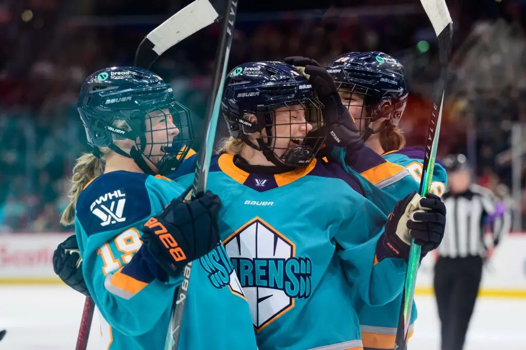 New York Sirens teammates celebrate a goal during a 2025/26 PWHL game.