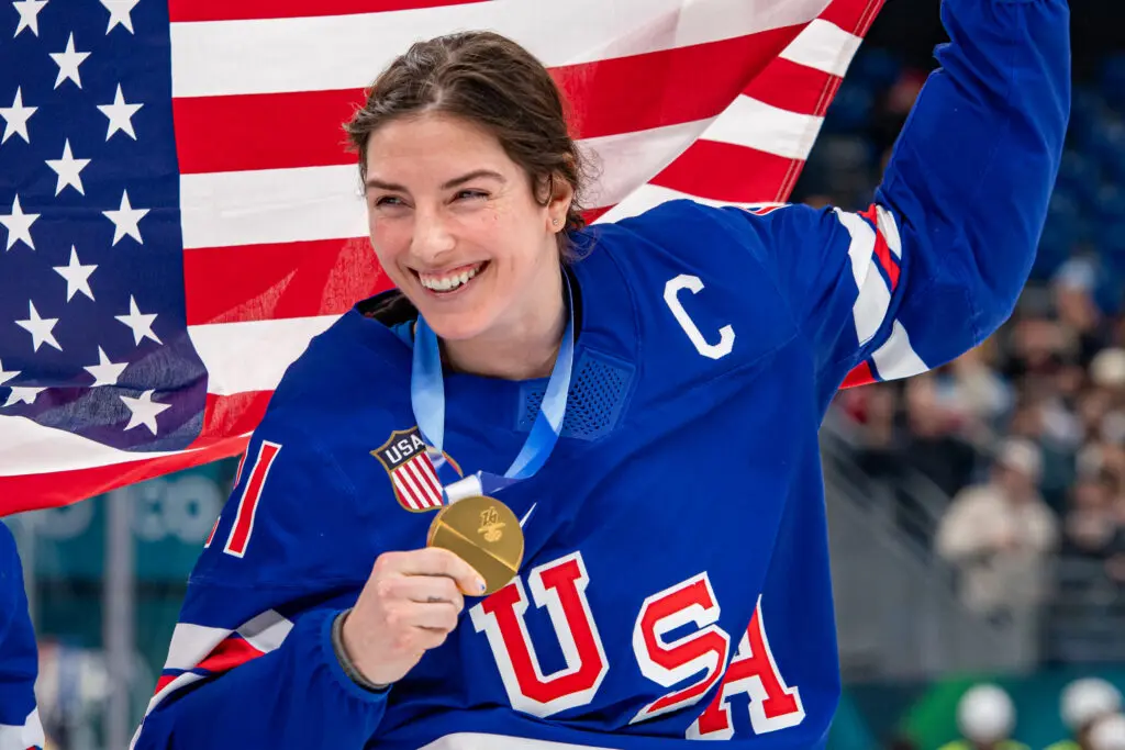 USA hockey captain Hilary Knight poses with her gold medal and a US flag at the 2026 Winter Olympics.