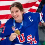 USA hockey captain Hilary Knight poses with her gold medal and a US flag at the 2026 Winter Olympics.