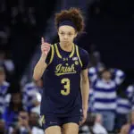 Notre Dame guard Hannah Hidalgo points intensely after sinking a three during a 2026 ACC women's basketball tournament game.