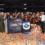 Texas women's basketball team and coaching staff pose with their 2026 March Madness Regional Championship trophy after their Elite Eight win.