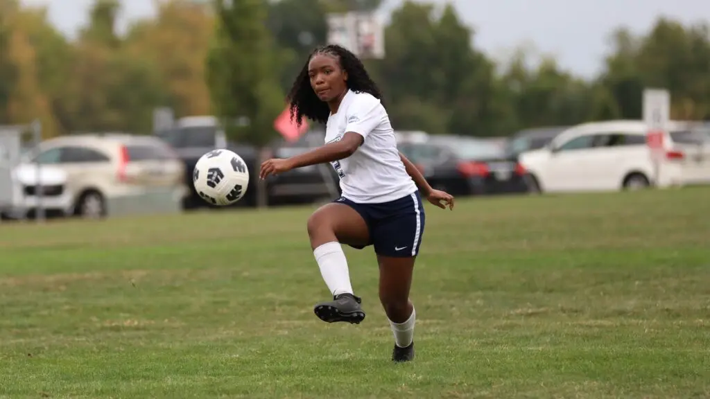 Penn State Women's Soccer Beaver player kicks a soccer ball on the pitch.