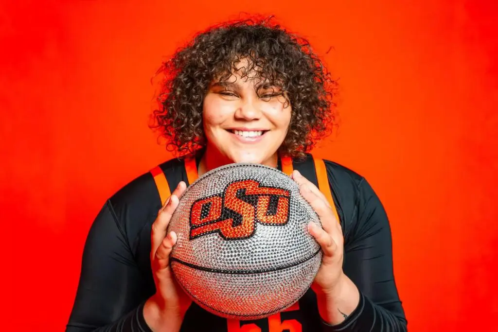 Oklahoma State NCAA transfer portal pickup Audi Crooks poses with a silver and orange OSU basketball against an orange backdrop.
