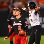 Oklahoma State's Audrey Schneidmiller (6) celebrates a double next to Nebraska's Lauren Camenzind (2) during the college softball game between the Oklahoma State University Cowgirls and the Nebraska Cornhuskers.