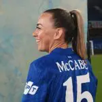 New Chelsea signing Katie McCabe poses in a Blue Chelsea FC jersey.
