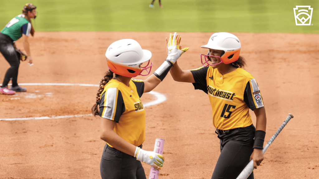 LLWS Southeast teammates high five after scoring a run.