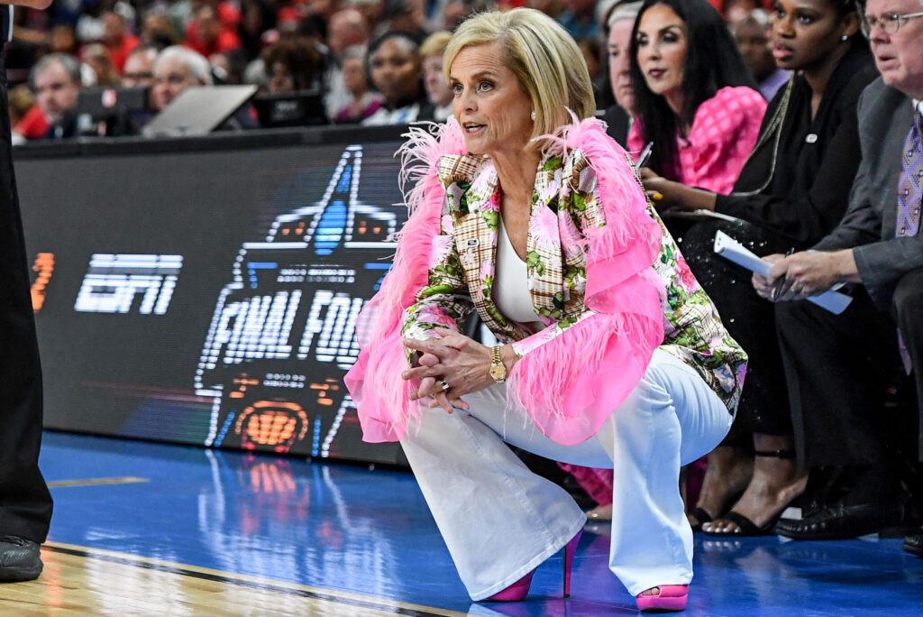 LSU women's basketball head coach Kim Mulkey wears a pink feather outfit on the sidelines of the NCAA tournament.