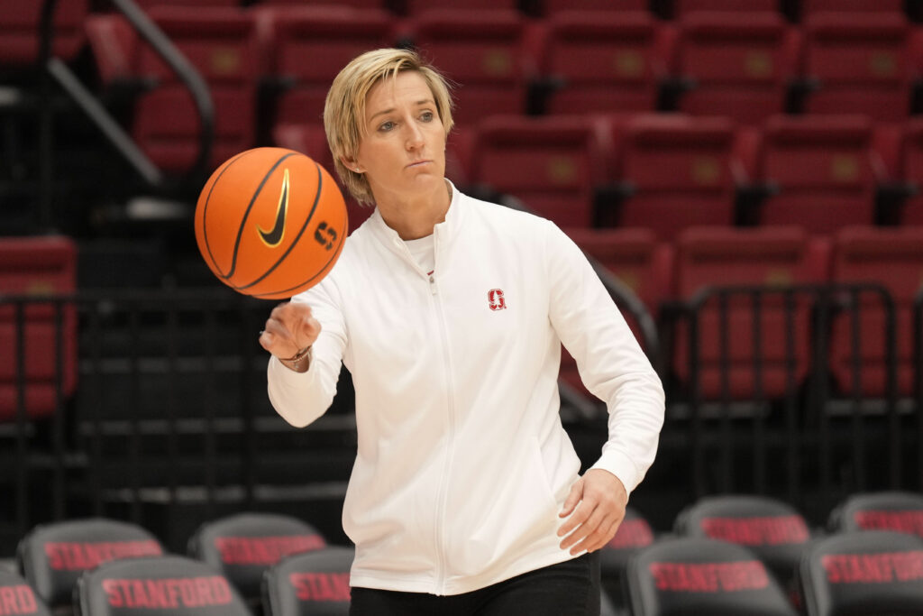 new stanford head coach kate paye spins a basketball on the court