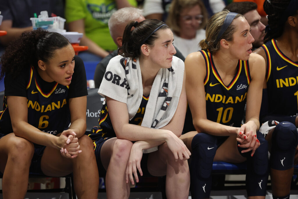 Caitlin Clark #22 of the Indiana Fever looks on from the bench while playing the Dallas Wings during a pre season game