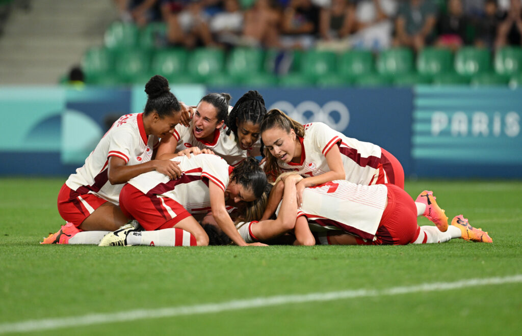 Team Canada collapses on Vanessa Gilles after winning against France at the Olympics