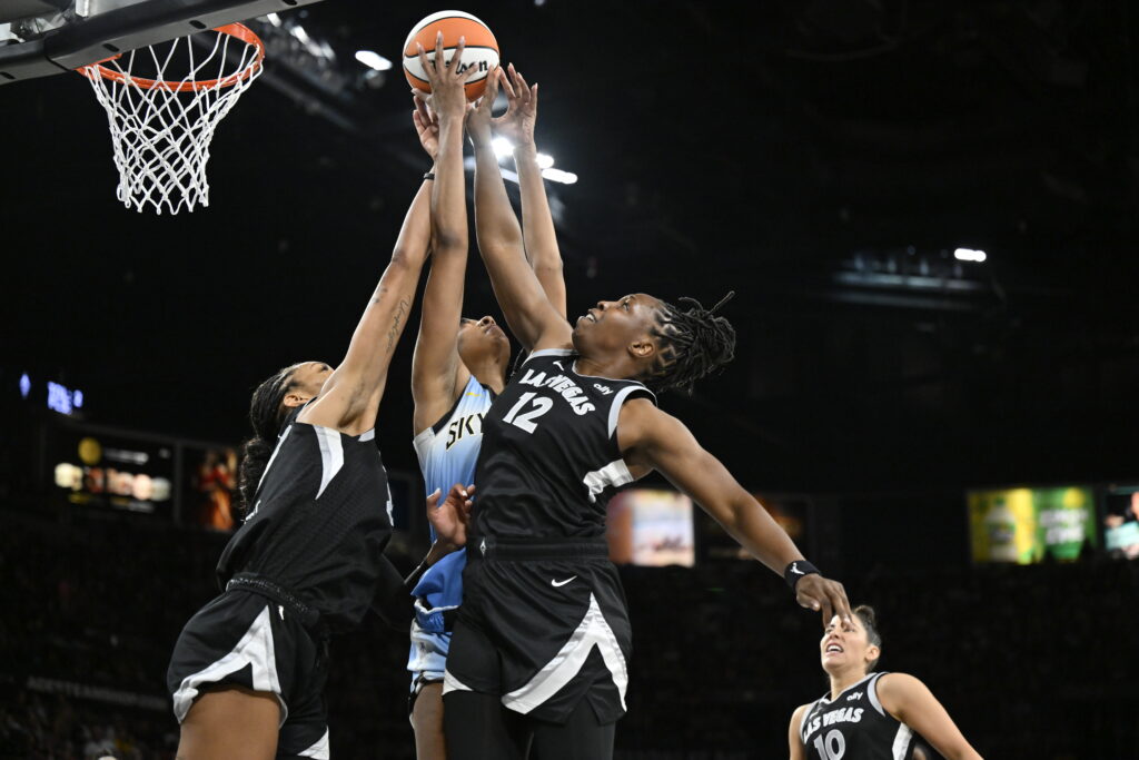 Chelsea Gray and other WNBA players jump up for a rebound.