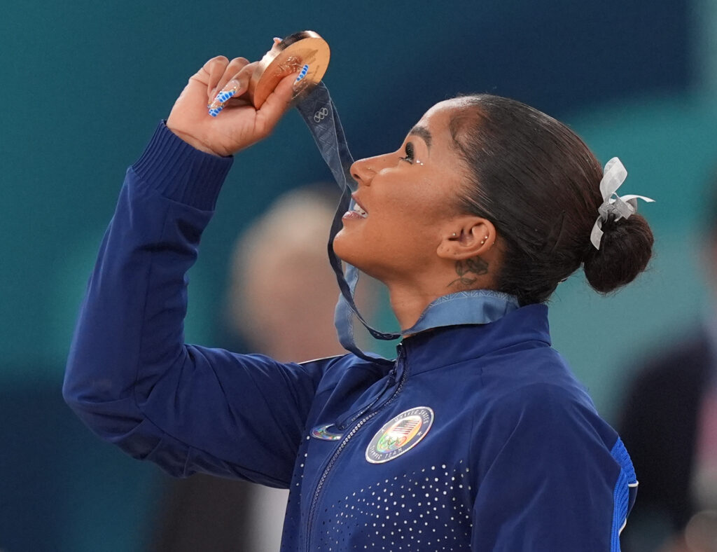 Jordan Chiles holds her Olympic floor bronze medal up to the light.