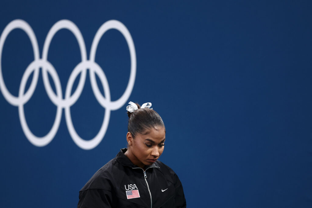 Jordan Chiles looks down with the five Olympic rings behind her