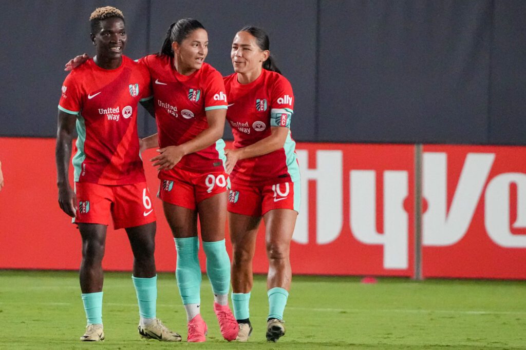 Kansas City Current midfielder Debinha (99) celebrates with forward Temwa Chawinga (6) and midfielder Lo'eau LaBonta (10) after scoring against the North Carolina Courage during the match at CPKC Stadium.