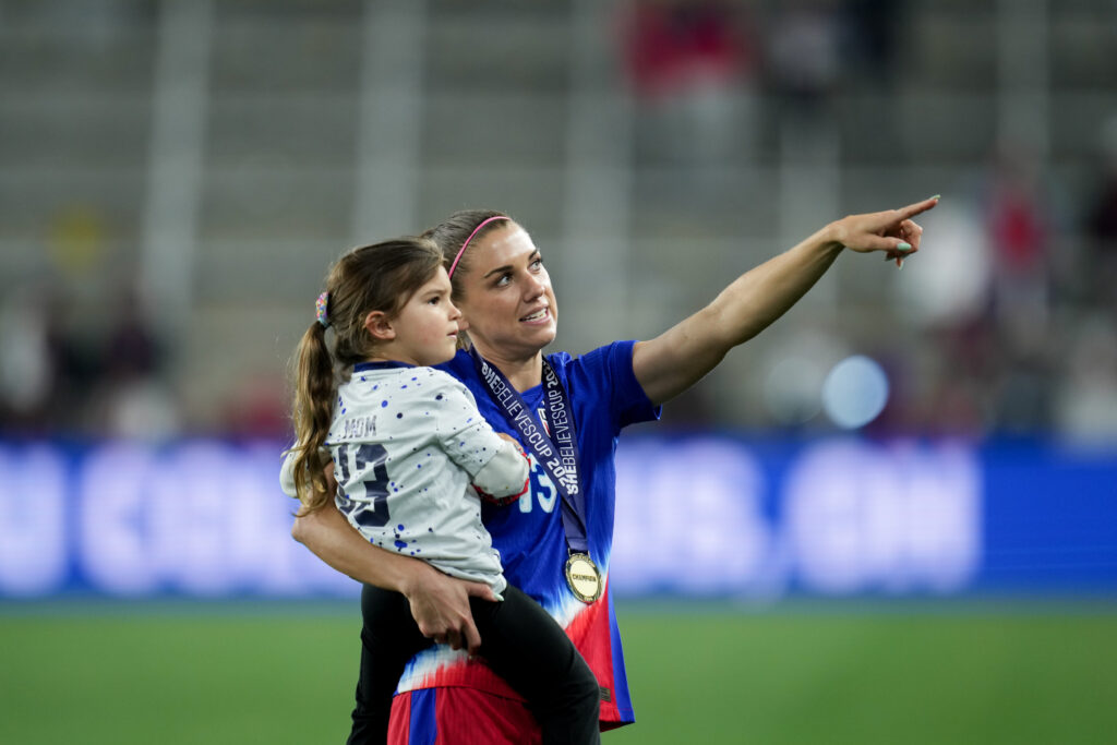 Alex Morgan celebrates a win while holding her daughter, Charlie.