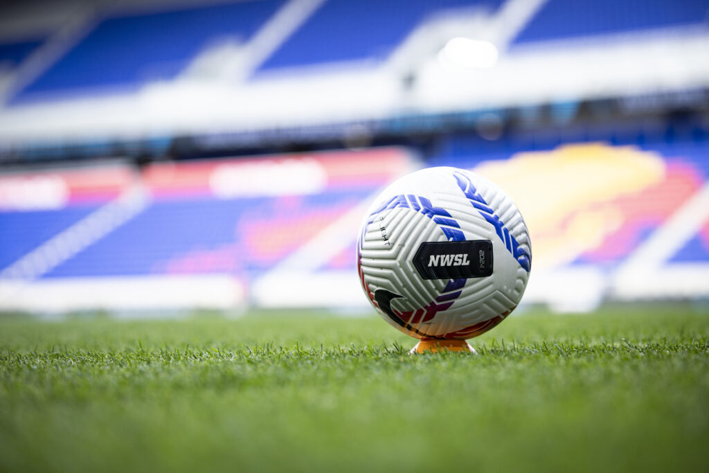 An NWSL game ball sits on the pitch before a match.