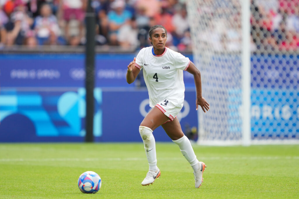 USWNT defender Naomi Girma looks upfield with the ball during a match.