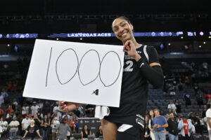 Las Vegas's A'ja Wilson smiles holding a sign with the number 1,000.