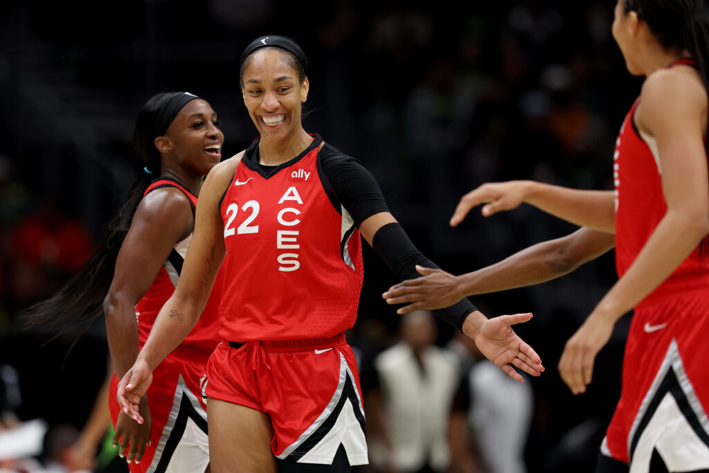 A'ja Wilson smiles and high-fives her Aces teammates during a game.