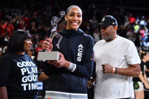 A'ja Wilson smiles holding her 2024 WNBA MVP trophy.