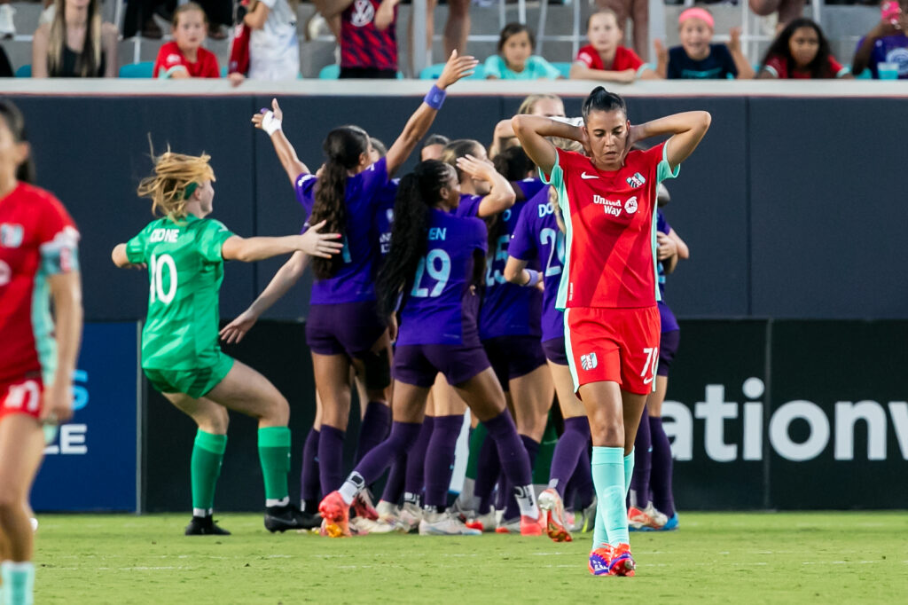 A Kansas City player reacts to the July 6th loss while Orlando celebrates in the background.