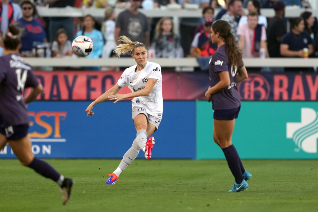 Bay FC center back Abby Dahlkemper passes the ball between two Racing Louisville players.