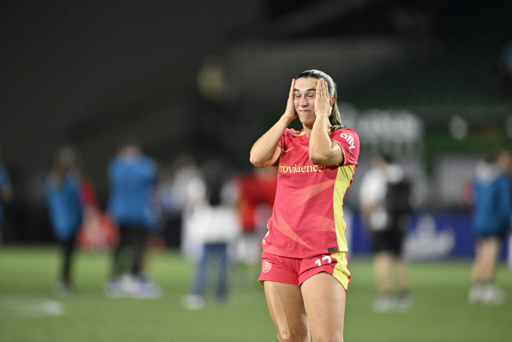 Portland midfielder Sam Coffey holds her head in her hands in frustration.