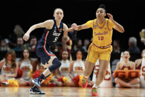 Preseason NCAA All-America team playersUConn's Paige Bueckers and USC's JuJu Watkins run down the court during a women's college basketball game.