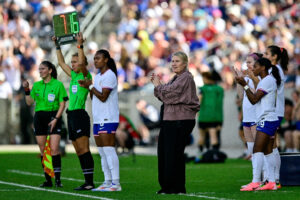 USWNT head coach Emma Hayes watches player substitutions during a match.