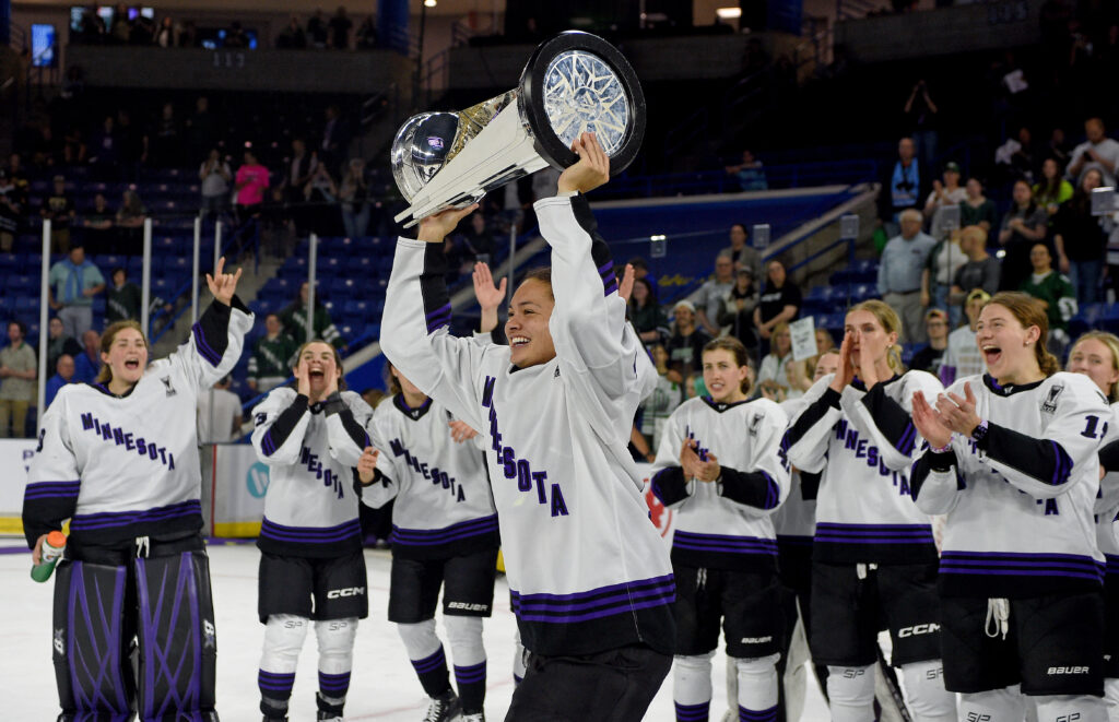 Minnesota's Sophie Jaques lifts the Walter Cup as her teammates cheer.