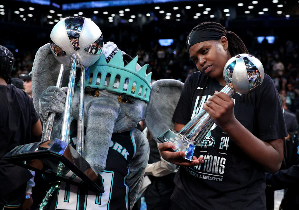 2024 WNBA Finals MVP Jonquel Jones poses with her trophy next to Liberty mascot Ellie.