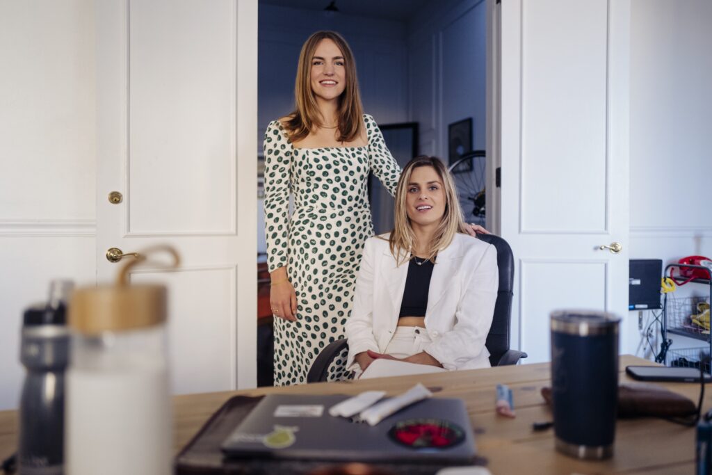 Sequel co-founders Greta Meyer and Amanda Calabrese pose behind a desk.