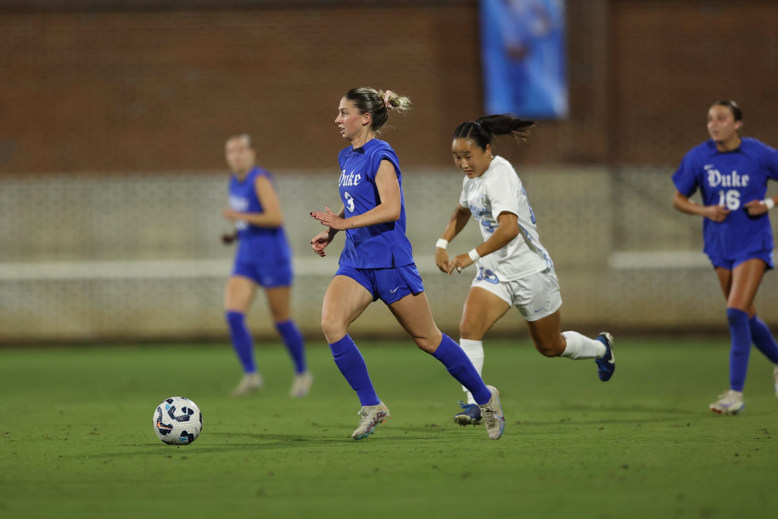 Duke forward Ella Hase dribbles past a UNC defender in a college soccer game.