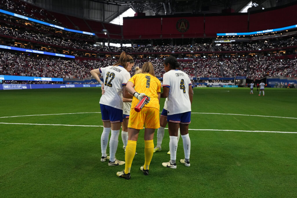 Tierna Davidson, Alyssa Naeher, and Naomi Girma huddle before a USWNT match.