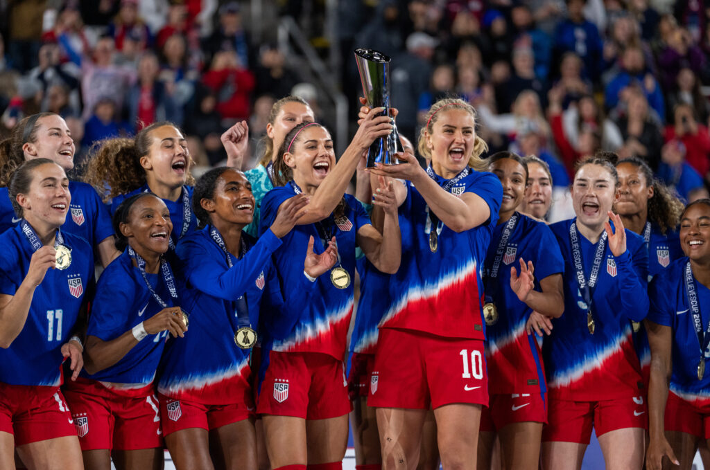 The USWNT raise their 2024 SheBelieves Cup trophy.