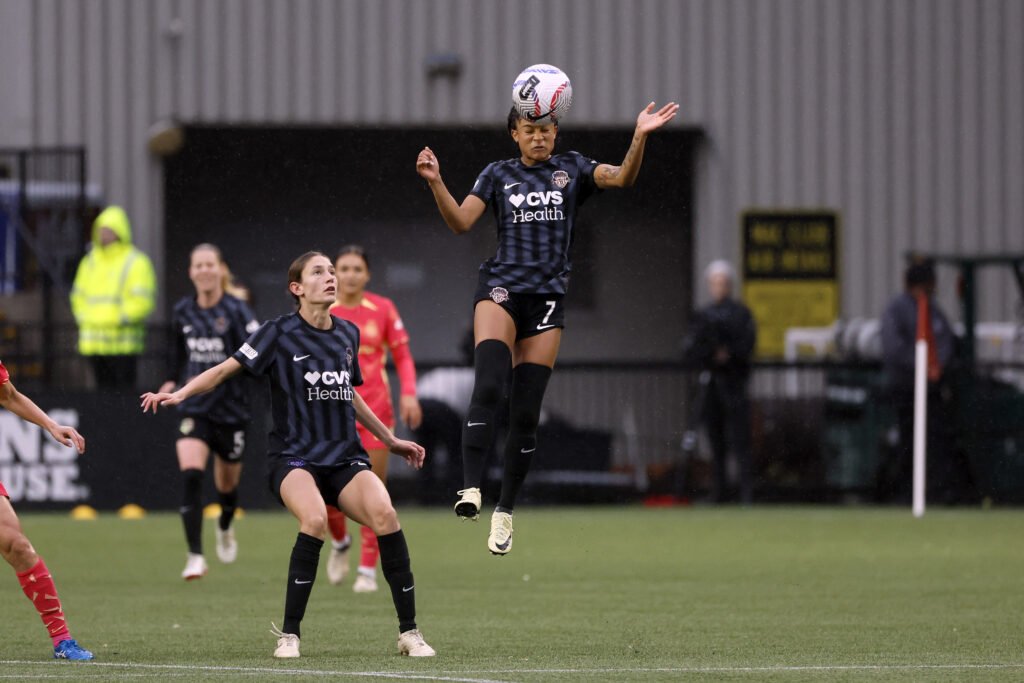 Washington rookie Croix Bethune leaps into the air for a header in an NWSL match.