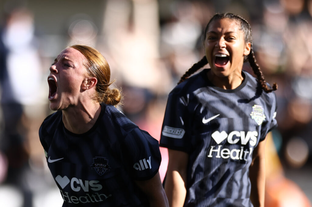 Washington rookie Hal Hershfelt celebrates a goal while teammate Makenna Morris looks on at an NWSL game.