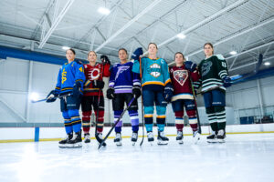 PWHL players pose on the ice while wearing new women's hockey uniforms.