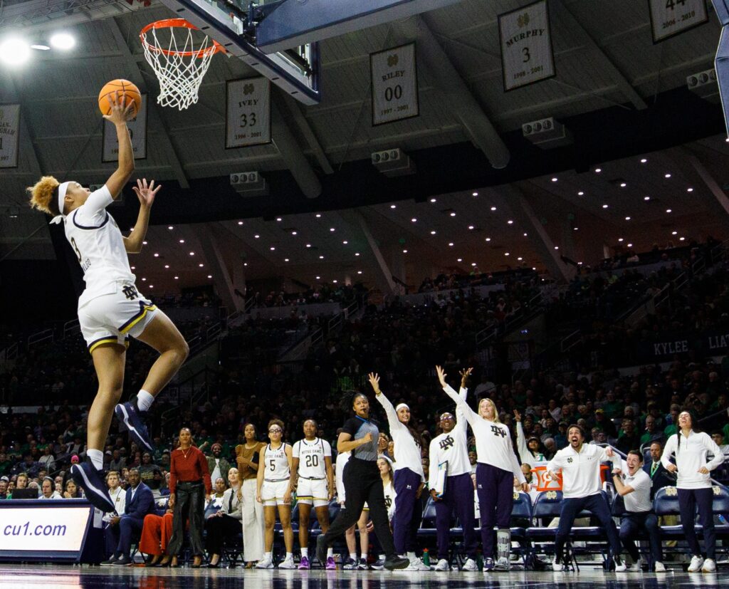 The Notre Dame bench cheers as guard Hannah Hidalgo puts up a lay-up in an NCAA college basketball game.