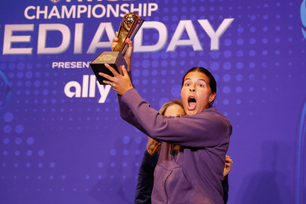 Orlando center back Emily Sams lifts her 2024 NWSL Defender of the Year trophy in the air.