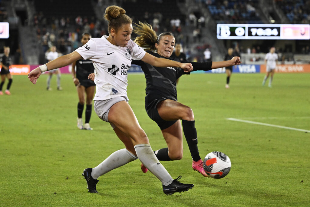 Angel City rookie Madison Curry looks to dispossess Bay FC's Savy King during a 2024 NWSL game.