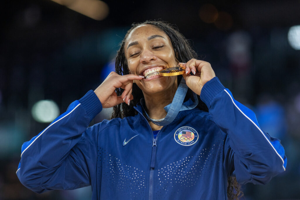 A'ja Wilson smiles while biting her 2024 Olympic gold medal.