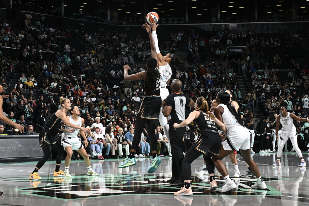 New York's Jonquel Jones and Las Vegas's A'ja Wilson leap for the ball to tip off a 2024 WNBA semifinal game.