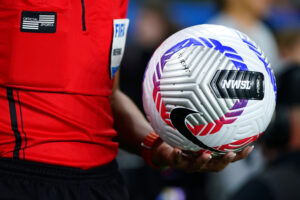 A referee holds an official NWSL soccer ball before a match.