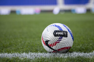 An NWSL game ball rests on the pitch.