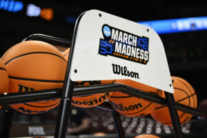 Official NCAA basketballs rest on a 2024 March Madness-branded stand.