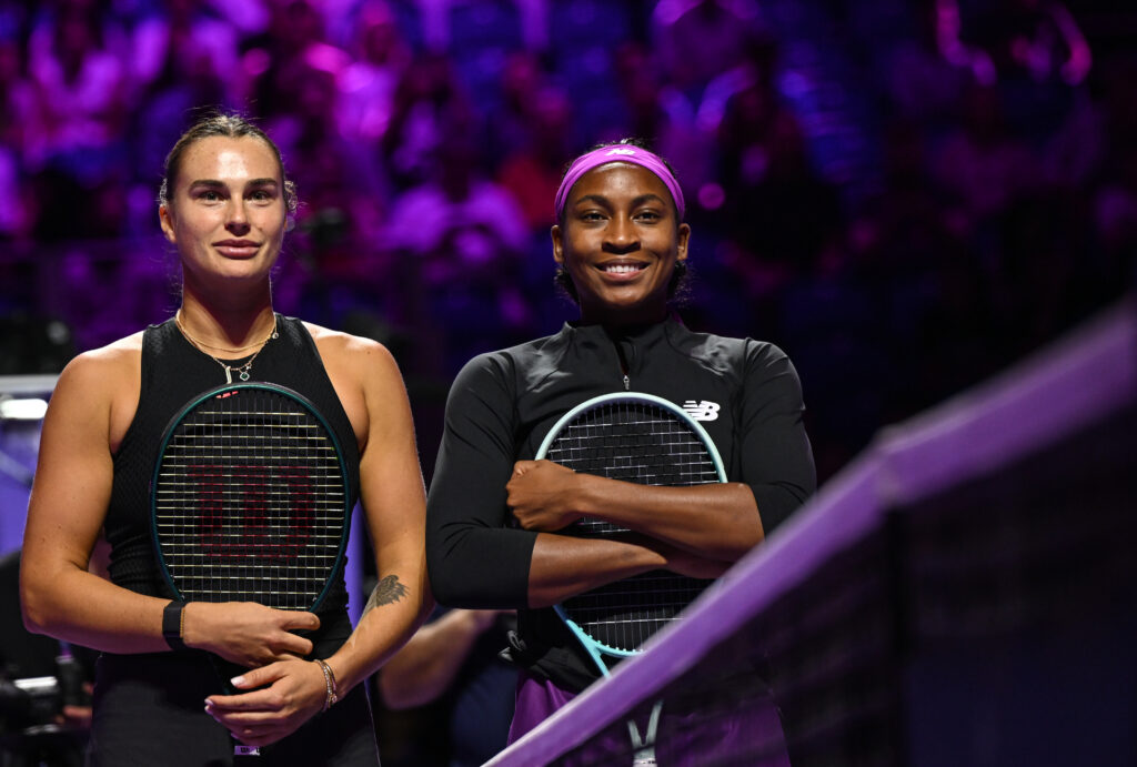 Tennis stars Aryna Sabalenka and Coco Gauff pose by the net before their 2024 WTA Finals match.