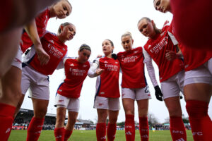 Arsenal's Kim Little talks to her team in a huddle.